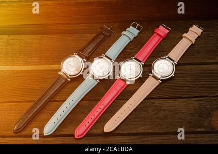 Set of multicolored women's wristwatches on a wooden table. Toning Stock Photo