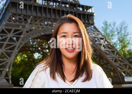 Asian girl in white T-shirt with braces looks at the camera and smiles, blurred background Stock Photo