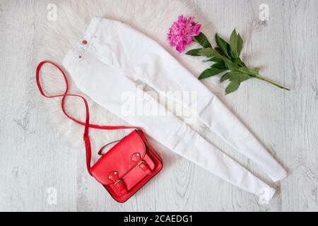 White jeans, red handbag and peony on a light background, fashionable concept Stock Photo