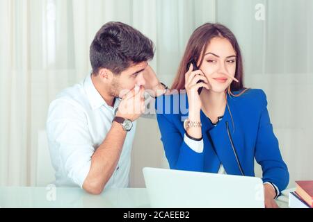 Young woman with extended nose having phone call and shocked man listening to her while sitting near Stock Photo