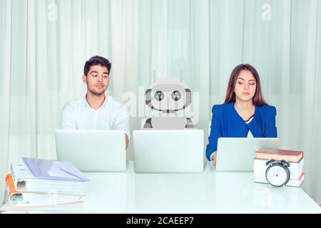 Young man and woman corporate employees with laptops sitting at table with robot colleague and peeking computer being envy about his much effective wo Stock Photo