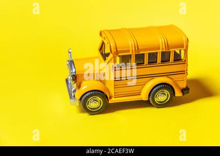 Simply design yellow classic toy car school bus isolated on yellow colorful background. Safety daily transport for kids. Back to school concept. Education symbol. Copy space Stock Photo