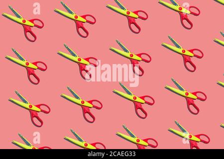 Open plastic yellow and red scissors on pastel pink color background. Seamless colorful pattern Stock Photo