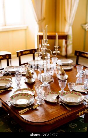 A festively decorated fish table with clean empty plates, spoons, knives, wine glasses, decanters and a candlestick in the center on a wooden table in Stock Photo