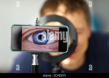 Man making video trying to shoot his own eye using modern smartphone camera Stock Photo