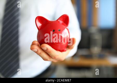 Male businessman hold in hand red little piggybank Stock Photo