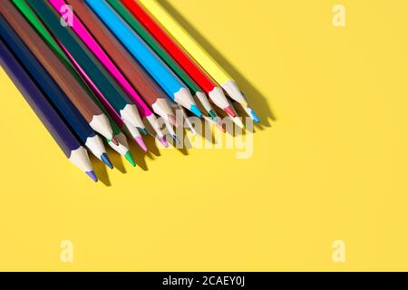 Colorful pencils for draw and study in school. Bright school supplies on yellow background. Stock Photo