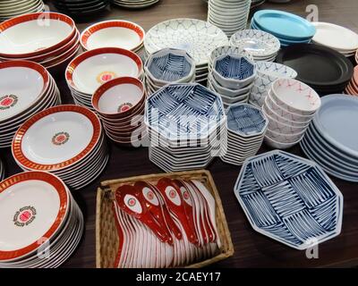Closeup shot of a variety of  colorful ceramic plates stacked and arranged on a wooden table Stock Photo