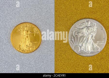 silver eagle and golden american eagle one ounce coins laying on silver and golden background, image split in two halves Stock Photo