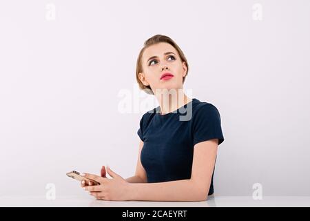 business through  phone,  girl types on  phone, excited and tense look, something puzzled and excited in thoughts Stock Photo