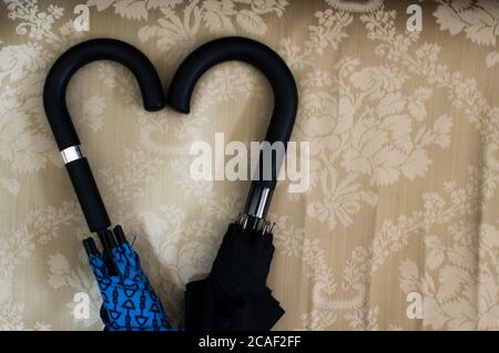 Top view closeup of two umbrella handles forming a heart shape