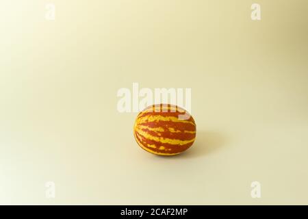 Small Vietnamese melon on a yellow background. Miniature fruit with pineapple flavor. Copy space. Horizontal orientation. Stock Photo