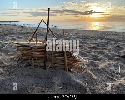 small hut made of straw on the sand by the sea at sunset Stock Photo