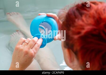 Redheaded woman in a hot tub bath checking the level of cleaning products Stock Photo