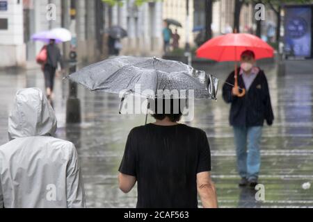 People under umbrellas walking the pedestrian street on a rainy summer day in the city of Belgrade, Serbia Stock Photo