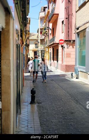Middle aged tourist couple holding hands while walking down a quiet narrow street in Granada, Spain. Stock Photo