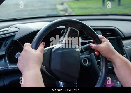 view of someone's hands on the proper position on the steering wheel while driving their car Stock Photo