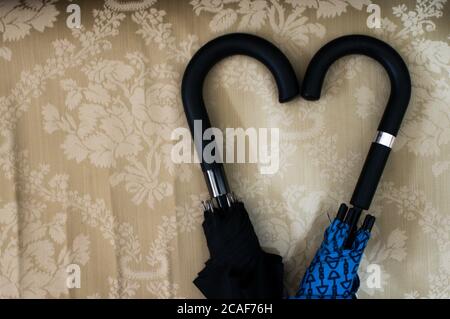 Top view closeup of two umbrella handles forming a heart shape