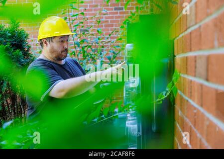 Electrician in yellow helmet technician checking by examining reading of meter on clipboard Stock Photo