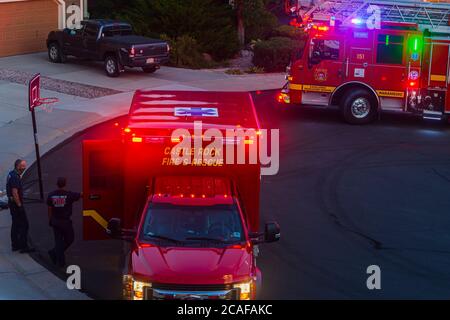 At night, two paramedics wait for elderly man to be taken from his home into their ambulance for transit to a hospital, Castle Rock Colorado USA. Stock Photo