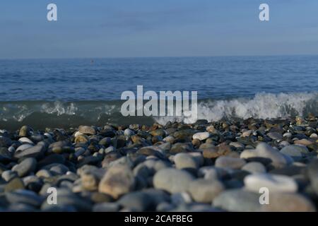 Seascape, view from the pebble shore on the rushing swirling wave. Stock Photo