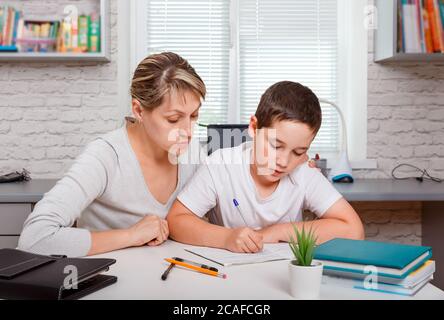 Woman helping his son with schoolwork. Homeschooling, online education Stock Photo