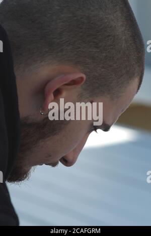 Young man with short hair cut and beard in a pensive mood Stock Photo