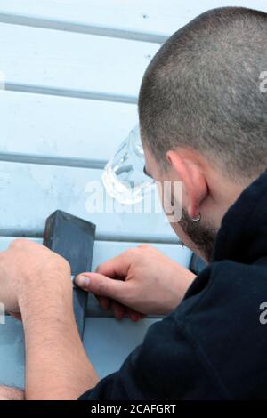 Closeup of a young man sharpening a knife using a whetstone Stock Photo
