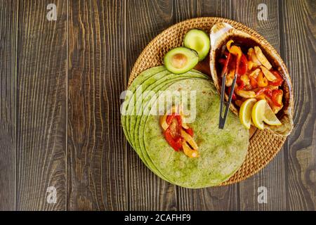 Spinach wrap with stir fry meat and vegetable on wood background. Stock Photo