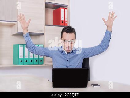 Young male entrepreneur celebrating his business success near a laptop Stock Photo