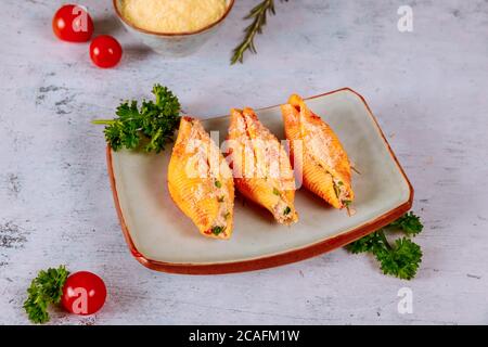 Three jumbo pasta on plate, stuffed with ricotta, tomatoes and parsley. Stock Photo