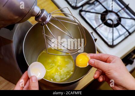 A woman separates egg white from egg yolk to make a sponge cake. Stock Photo