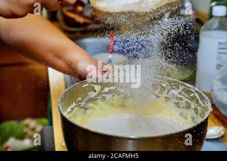 Woman sifts the flour in mixer bowl with dough. Making cake dough. Stock Photo