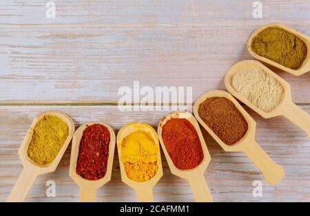 Assortment of colorful spices in the wooden spoons on wooden background. Stock Photo