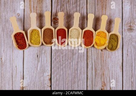 Eight wooden spoons of asian spices on white wooden table. Stock Photo