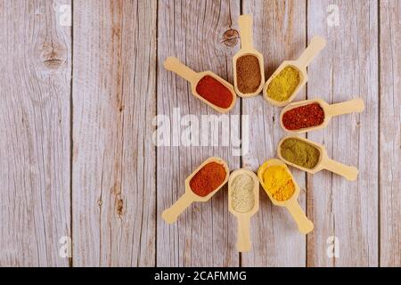 Assortment of spices in wooden spoons on white wooden background. Stock Photo