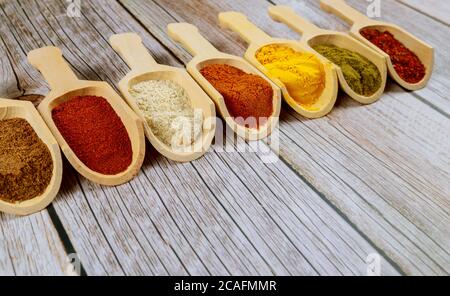 Various colorfull spices in wooden spoons on a wooden table. Stock Photo