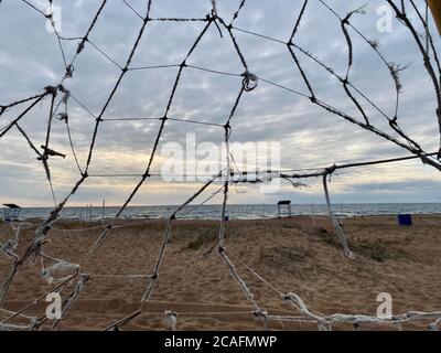 old torn soccer net on a deserted beach Stock Photo