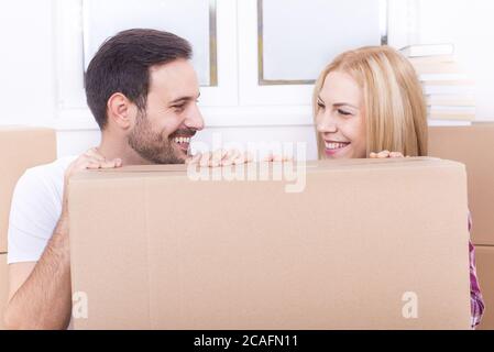 A young couple moves into their new apartment. They are surrounded by ...