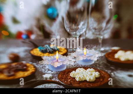 Christmas night. Burning candles on the dinning table with food, decorated Christmas tree. Stock Photo