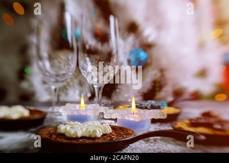 Burning candles on the dinning table with food, decorated Christmas tree. Christmas night. Stock Photo