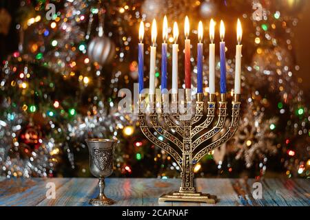 Menorah with burning candles for Hanukkah on sparkle background with defocused colorful lights. Jewish holiday. Stock Photo