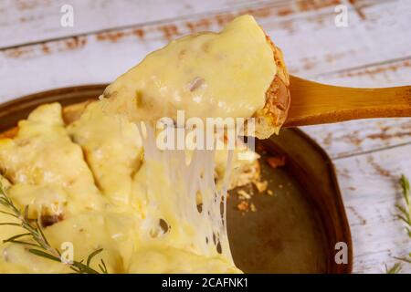 Slice of hot cheese pizza on shovel with melted cheese. Stock Photo