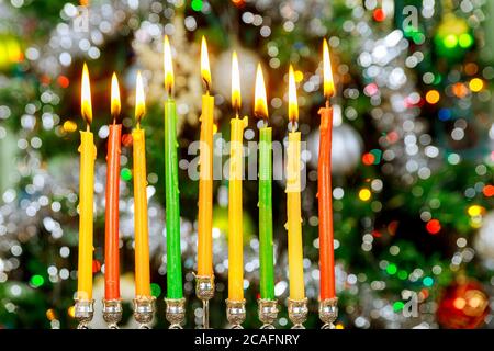 Menorah with burning candles for Hanukkah on sparkle background with defocused colorful lights. Jewish holiday. Stock Photo