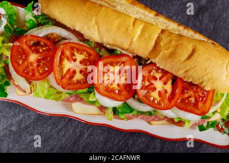 Sub sandwich with salami, cheese and vegetable on black background. Stock Photo