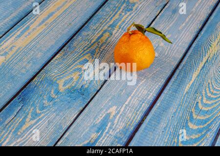 One tangerine with green leaf on wooden table. Stock Photo