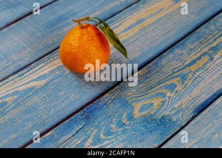 One tangerine with green leaf on wooden table. Stock Photo