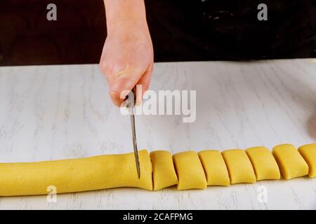 Woman cuts with a knife in equal portions for baking dinner rolls. Stock Photo