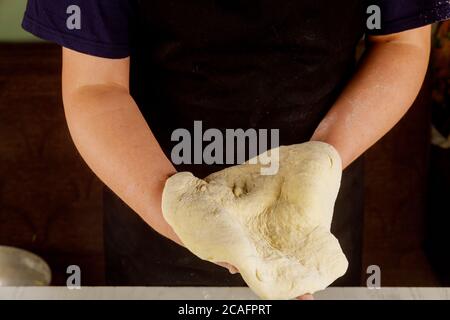 Raw pizza dough in chefs hands for making pizza. Stock Photo