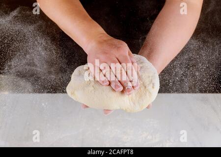 Chef kneading pizza dough in hands for pizza making. Stock Photo